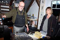 Peter Dettmann erläutert Besuchern seiner Werkstatt den Druck einer Lithografie